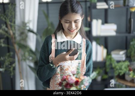 Fiorista asiatica felice, startup, piccola impresa, PMI di successo nel negozio di fiori Foto Stock