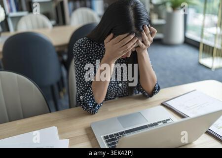 Concetto di sindrome di Burnout. La donna d'affari asiatica tocca la fronte, ha mal di testa, lavoro noioso e stanca, dolore emotivo e lavoratore depresso Foto Stock