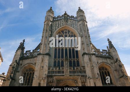 Vista architettonica dall'angolo basso della grandiosa facciata del fronte occidentale dell'Abbazia di Bath con le sue grandi vetrate colorate a Bath, Somerset, Regno Unito Foto Stock