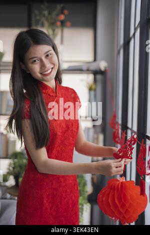 Bella giovane donna asiatica vestiti rossi che fanno carta rosso lanterna di Capodanno cinese per le decorazioni lunari del nuovo anno feste di Capodanno cinese per buon luc Foto Stock
