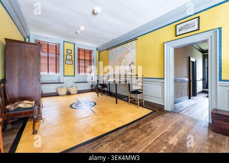 Quartieri familiari di Carlyle House Interno coloniale Vecchia città di Alexandria Stati Uniti | ALEXANDRIA, Virginia — Un pavimento in tela dipinto con un motivo a rosa dei venti copre le assi nel quartiere familiare al piano superiore del Carlyle House. Completato nel 1753 dal mercante scozzese John Carlyle, la residenza è stata un punto di riferimento nella città portuale coloniale. Il motivo marittimo del pavimento e la mappa murale adiacente del Nord America fanno riferimento diretto alla rete di navigazione transatlantica che ha generato la sua fortuna. Foto Stock