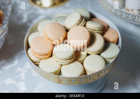 Macaron pastello accoccolati in un'elegante ciotola a motivi geometrici Foto Stock