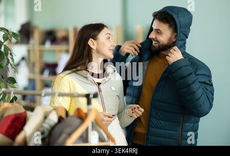 Coppia che prova le giacche in un negozio di abbigliamento Foto Stock
