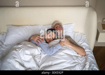 Fiducia, amore e vicinanza nelle relazioni con gli anziani, uomo anziano e donna che abbracciano mentre dorme Foto Stock