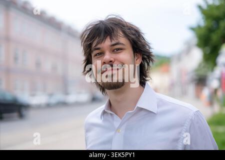 Ritratto positivo di giovane uomo con barba su sfondo urbano sfocato Foto Stock