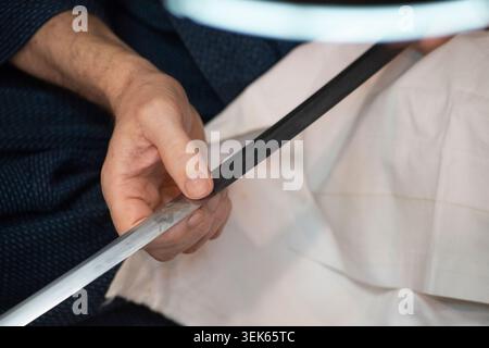 L'uomo pulisce Blade dalla tradizionale spada giapponese Katana Foto Stock