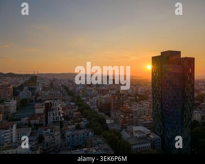 Vista aerea del moderno skyline di Tirana con un grattacielo di rilievo durante un tramonto dorato sulla città e sulle montagne lontane Tirane, Tirana Foto Stock