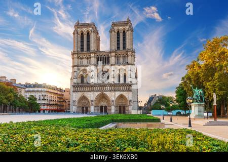Panorama serale mozzafiato della cattedrale di Notre-Dame a Parigi, incorniciata da alberi verdi vibranti sotto un suggestivo cielo al tramonto Foto Stock