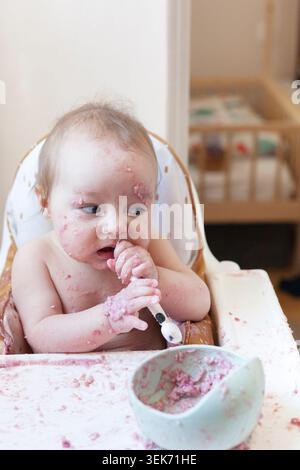 Il bambino esplora il cibo e si allatta da solo durante l'ora dei pasti Foto Stock
