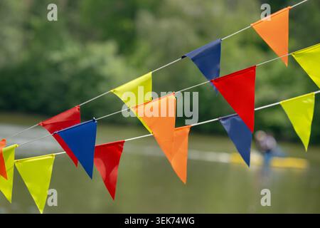 Bandiere a grappolo di colore rosso giallo blu e verde appese all'esterno con sfondo sfocato. Foto Stock