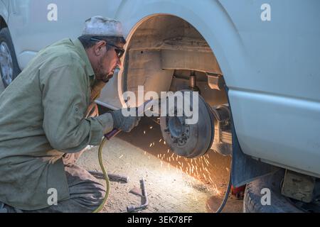 Meccanico afgano che ripara auto sulla strada hindu kush Foto Stock