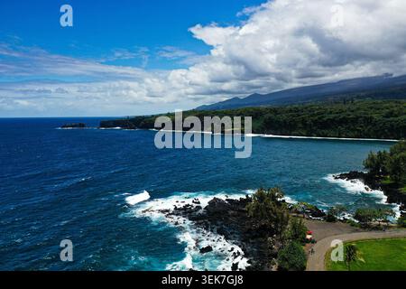 Una vista aerea che cattura l'aspra costa di Maui, Hawaii. Le vibranti acque blu dell'Oceano Pacifico incontrano la lussureggiante vegetazione dell'isola, con Foto Stock