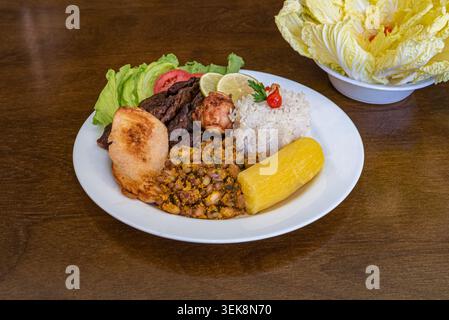 Feijoada brasiliana servita su piatto bianco. Include riso, manioca, fagioli e carne. Attenzione al concetto di cucina. Promuove il benessere e l'alimentazione sana. Stu Foto Stock