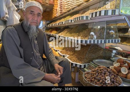 Uomo che vende frutta secca e noci in un mercato tradizionale Foto Stock