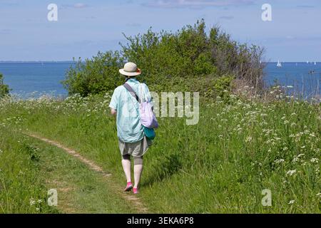 Donna che cammina lungo il sentiero escursionistico lungo la costa del Mar Baltico, Altbülk, Strande, Schleswig-Holstein, Germania Foto Stock