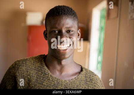 ritratto di un giovane uomo africano sorridente di luce naturale in un ambiente d'ufficio africano, concetto di gioventù del senegal Foto Stock