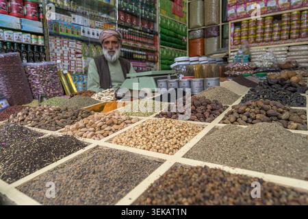 Persona che vende varie spezie, noci ed erbe nel tradizionale negozio di bazar con molti prodotti per uso culinario e benessere. Foto Stock