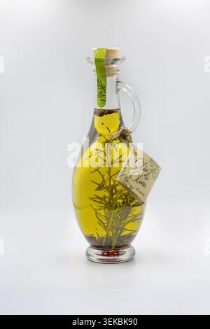 Kiev, Ucraina - 11 aprile 2024: Caraffa decorativa in vetro di olio extra vergine di oliva olio di oliva infuso con rametti e spezie di rosmarino fresco, editori Foto Stock