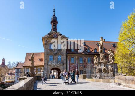 Bamberga, Baviera, Germania - 7 aprile 2026: Le persone camminano vicino al municipio di Bamberga e alla statua di Christus in una giornata di sole Foto Stock