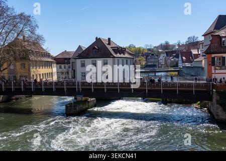 Bamberga, Baviera, Germania - 7 aprile 2026: I visitatori camminano su un ponte sopra un canale di Bamberga con l'acqua sottostante Foto Stock