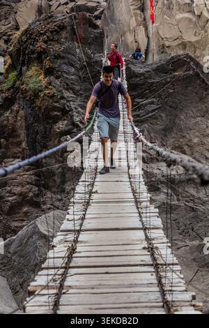 TIGER LEAPING GORGE, CINA - 10 NOVEMBRE 2019: Escursionista su un ponte sospeso sul fiume Jinsha nella Tiger Leaping Gorge, provincia dello Yunnan, Cina Foto Stock