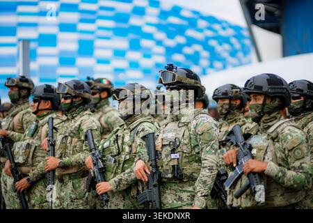Il personale militare armato che indossa attrezzature mimetiche tattiche si trova in formazione per la sicurezza durante un evento sportivo di massa allo stadio Foto Stock