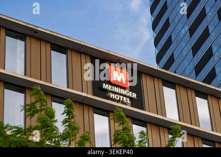 Amsterdam, Paesi Bassi: Vista ravvicinata del logo rosso e bianco e del segno del Meininger Hotel su una moderna facciata in bronzo e vetro. Foto Stock