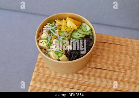 Tofu, ananas, mango, sottaceti di cetriolo, alghe nere o funghi di legno, cipolla rossa, cipolla primaverile, semi di sesamo, base di riso, condimento piccante. Foto Stock