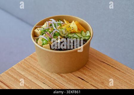 Tofu, ananas, mango, sottaceti di cetriolo, alghe nere o funghi di legno, cipolla rossa, cipolla primaverile, semi di sesamo, base di riso, condimento piccante. Foto Stock