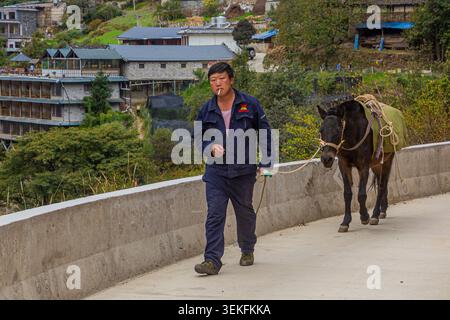 TIGER LEAPING GORGE, CINA - 10 NOVEMBRE 2019: Uomo locale con un cavallo nella Tiger Leaping Gorge, provincia dello Yunnan, Cina Foto Stock