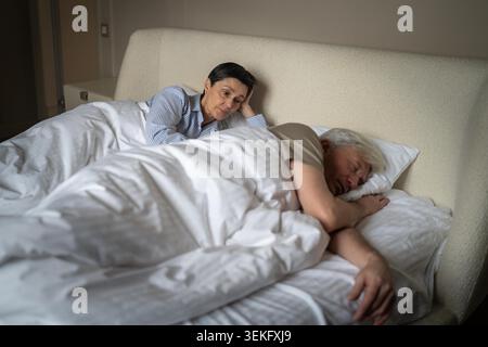 Infelice penosa anziana donna che perde il sonno per eccesso di pensiero e dubbi sul marito che tradisce, coppia anziana sposata sdraiata a letto in camera da letto moglie anziana stressata dai pensieri sulla relazione d'amore del partner. Foto Stock