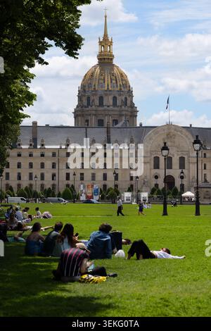 Le persone si rilassano sul prato accanto a Les Invalides e alla sua cupola dorata a Parigi. Foto Stock