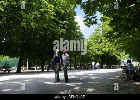 La coppia cammina mano nella mano sotto gli alberi frondosi nel Jardin du Luxembourg a Parigi. Foto Stock