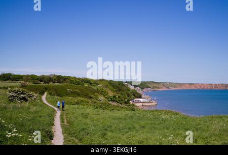 Una coppia più anziana cammina sul sentiero costiero sopra la spiaggia di Filey Foto Stock