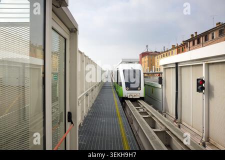 Bologna, Italia - 3 marzo 2026: Il treno automatizzato della monorotaia Marconi Express si avvicina alla stazione di Bologna centrale su un binario sopraelevato, con Bologna città Foto Stock