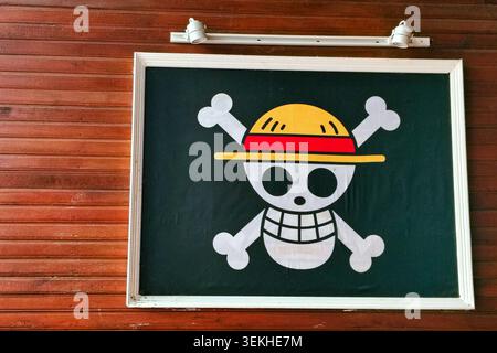 palu, Indonesia - 31 maggio 2026: Logo Jolly Roger incorniciato dei pirati del cappello di paglia dalla famosa serie manga e anime giapponese One Piece, esposto su una parete di pannelli di legno Foto Stock