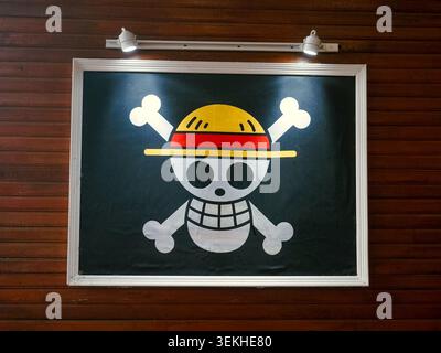 palu, Indonesia - 31 maggio 2026: Logo Jolly Roger incorniciato dei pirati del cappello di paglia dalla famosa serie manga e anime giapponese One Piece, esposto su una parete di pannelli di legno Foto Stock
