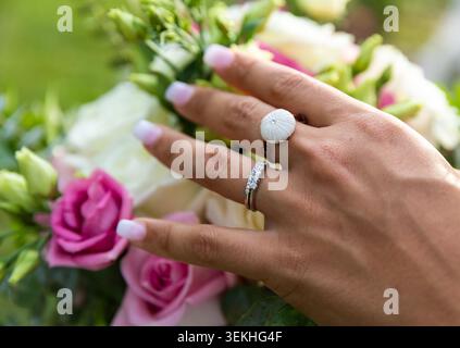 Primo piano della mano di una donna con anelli eleganti, tra cui un anello di tendenza ispirato alla conchiglia e un cinturino con diamanti Foto Stock