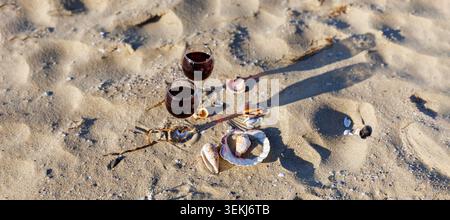 Vista artistica dall'alto dei bicchieri da vino sulla spiaggia con conchiglie Foto Stock