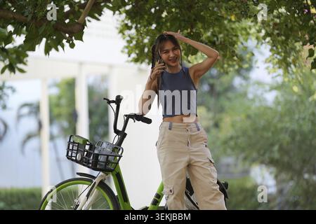 La giovane donna asiatica felice pedala in bicicletta nel parco, nella città di strada il suo sorriso utilizzando la bicicletta di trasporto, eco-friendly, concetto di stile di vita ecologico per le persone Foto Stock