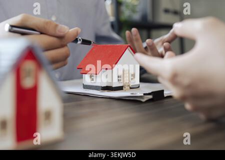Agente immobiliare e cliente che parlano del concetto di assicurazione immobiliare e sicurezza su casa a cliente prima di firmare il contratto Foto Stock