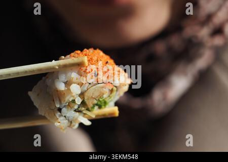 Mangiare sushi con bacchette in un ambiente informale Foto Stock