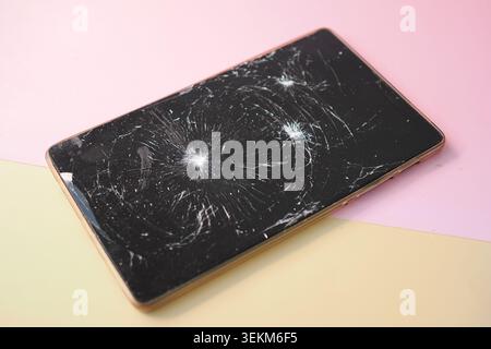 Smartphone con uno schermo incrinato su uno sfondo colorato Foto Stock