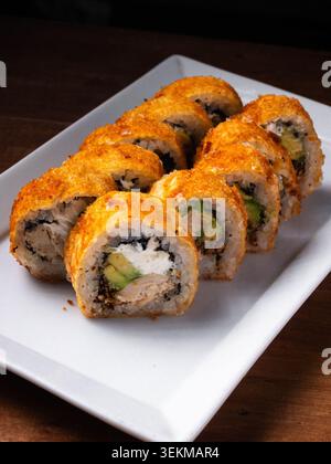 I panini dorati poggiano su un piatto bianco pulito. L'esterno croccante nasconde ripieni cremosi all'interno. Ogni fetta mostra avocado e formaggio cremoso. Plat Foto Stock