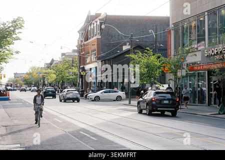 Toronto, Canada - 26 maggio 2026: Affollata Queen Street West con ciclisti Cars e pedoni nella Sunny Evening Foto Stock
