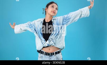 Giovane donna attiva che si allunga le braccia spalancate ballando all'interno dello studio fotografico Foto Stock