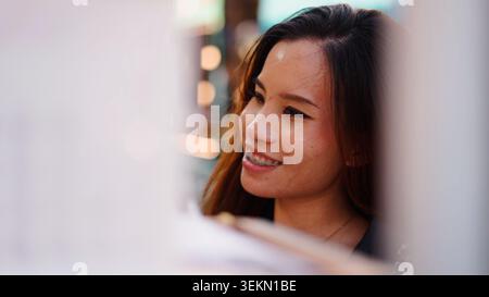 Giovane donna asiatica che sorride, indossa l'apparecchio, mostra felicità ed emozioni positive Foto Stock