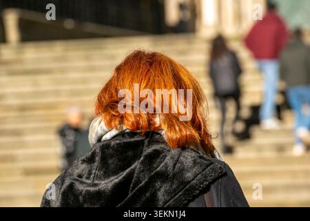 Donna irriconoscibile con i capelli tinti ardenti su una strada della città Foto Stock