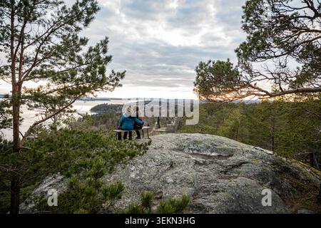 Vista ad alto angolo di madre e figlia sedute con il braccio l'una intorno all'altra sulla collina sotto il cielo nuvoloso Foto Stock