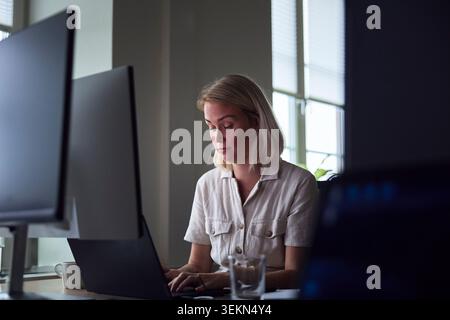 Professionista donna dai capelli corti che lavora su un notebook in ufficio Foto Stock